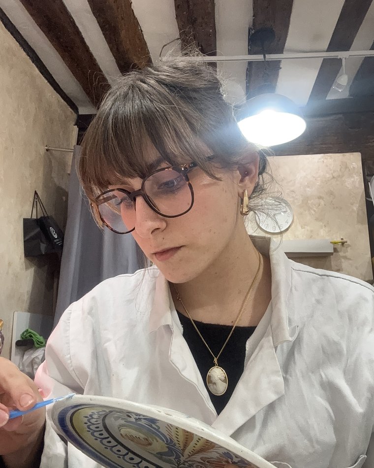 Tiffen Rivalin en train de retoucher une assiette en faïence à l'atelier