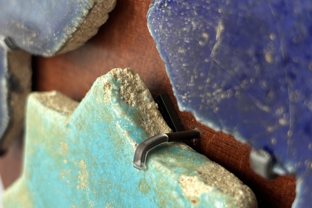 Détail du soclage mural : attaches métalliques maintenant les carreaux sans perçage
